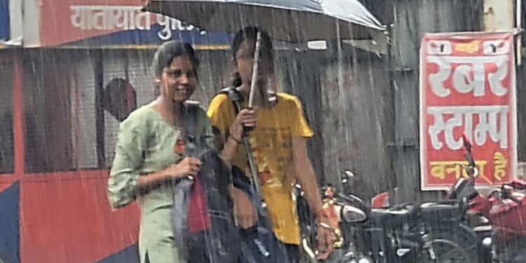 रणधीर वर्मा चौक पर बारिश से बचने का प्रयास करती युवतियां