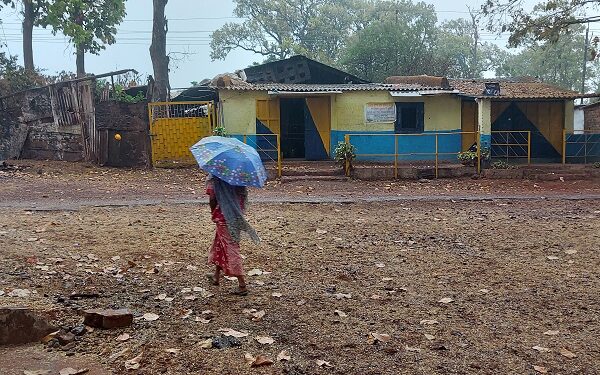 वर्षा के बीच छाता लिये जाती एक महिला