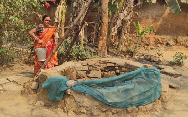 गांव के कच्चे कुएं पानी भरती महिला.