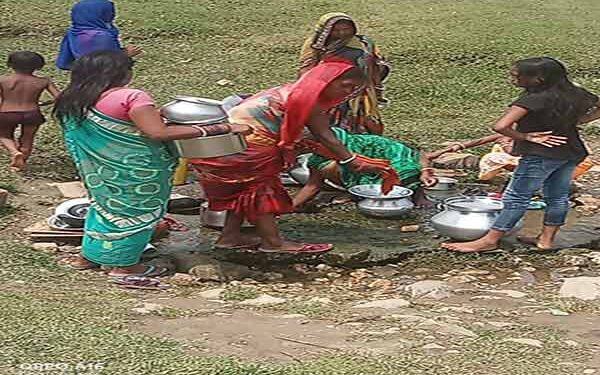 चुंआ से पानी भरती आदिवासी महिलाएं