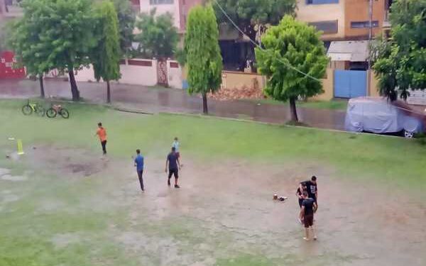 वर्षा के दौरान साकची में क्रिकेट खेलते बच्चे