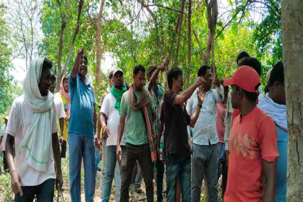 जंगल में पेड़ काटने का विरोध करते आदिवासी युवक